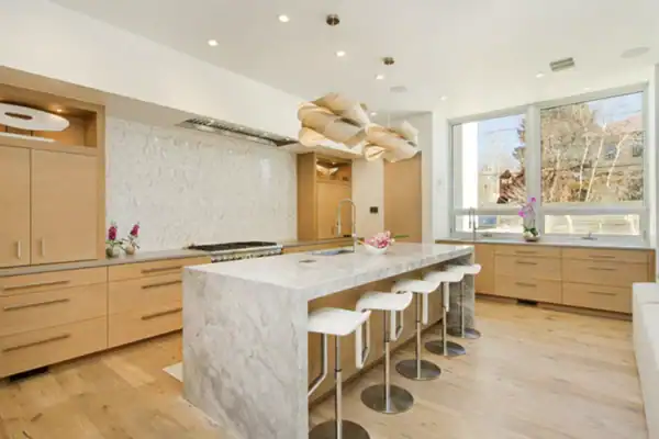 bright, modern kitchen with large wood cabinets, unique light fixtures, and marble island with white stools ONE Residential Builders Denver