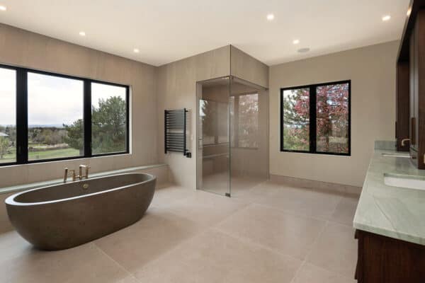 clean lines in contemporary bathroom with glass shower door, dual sinks, and soak tub ONE Residential Builders Denver