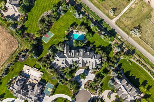 true aerial view of new home build highlighting new roof, pool, mature trees, and sport court with neighbors to either side ONE Residential Builders Denver