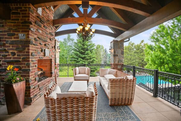 new home patio with large fire place, modern wicker furniture, tile flooring and pool ONE Residential Builders Denver