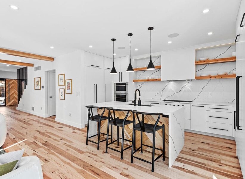 hero image of open concept kitchen with modern, white finishes and wood paneling under the island area ONE Residential Builders Denver