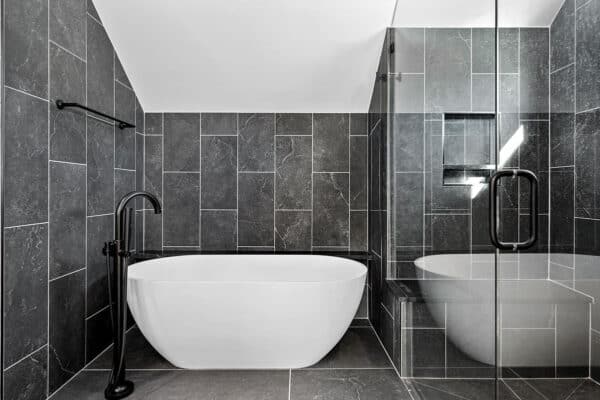 modern bathroom with dark gray tile and large soak tub ONE Residential Builders Denver